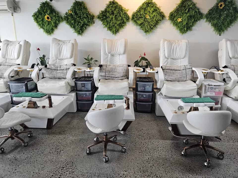 Row of pedicure spa massage chairs beneath sunflower wall decor